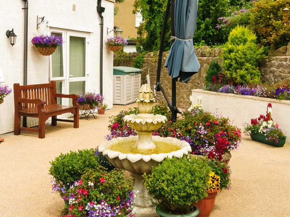 The courtyard garden at Albert House, with a fountain, benches and raised flower beds