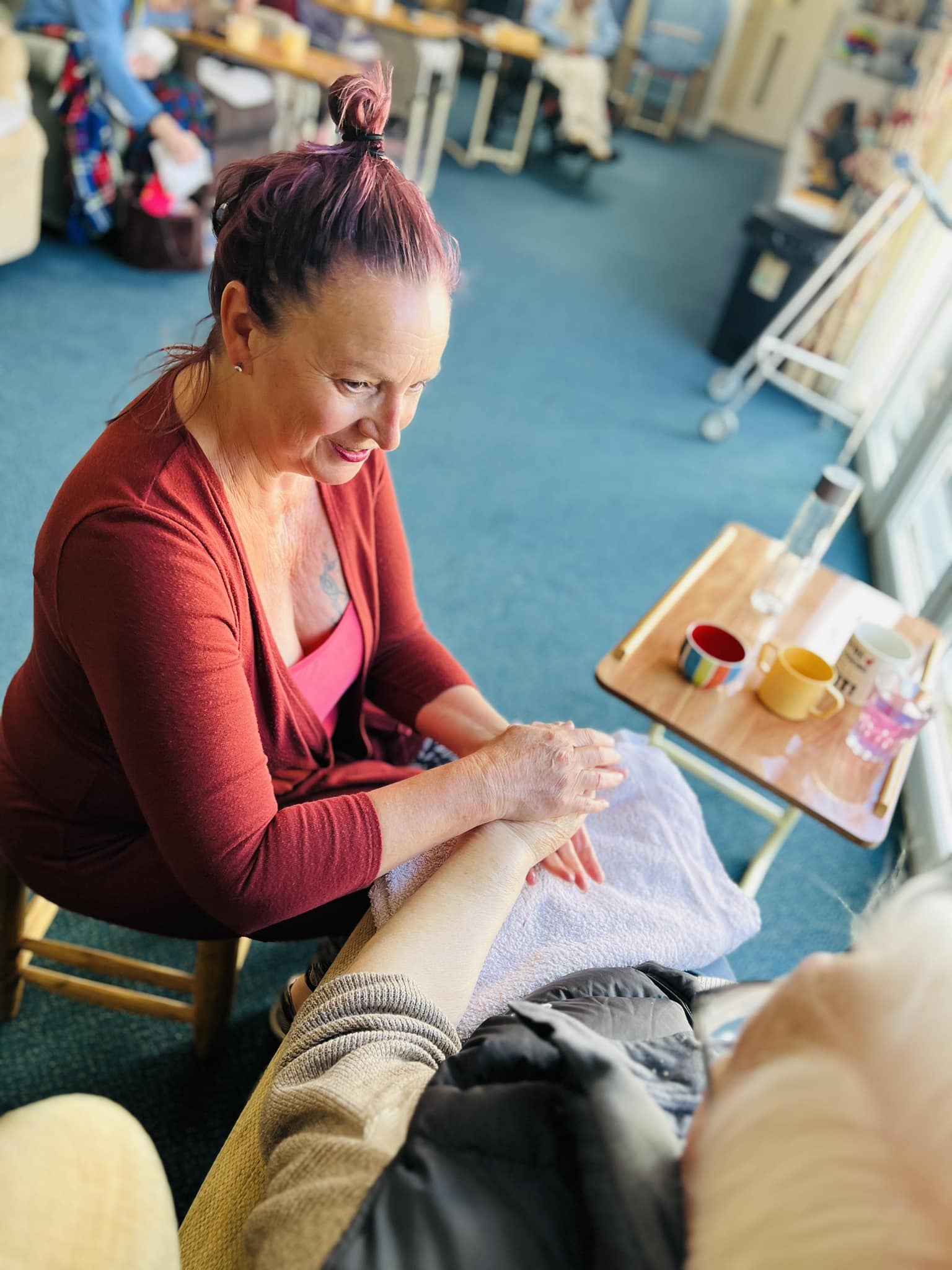 A carer giving a resident a hand massage in her room