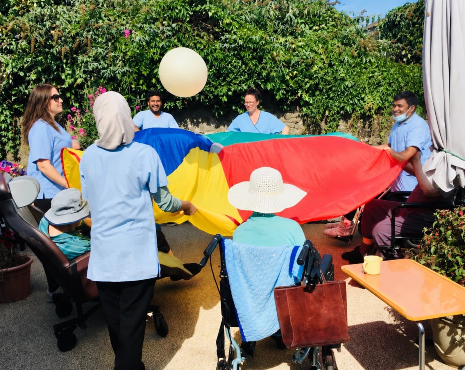 Residents and staff playing a parachute game in the garden